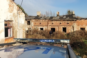 policyjny oznakowany radiowóz na tle stojących dalej pustostanów.