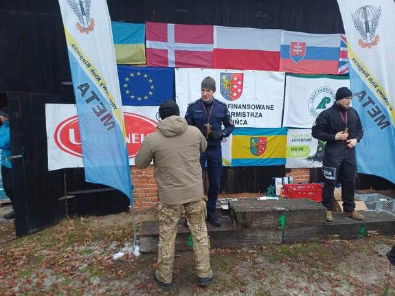 Umundurowany policjant stojący na podium, otrzymuje statuetkę.