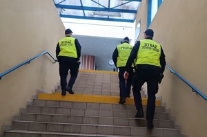 Umundurowani policjanci wraz z funkcjonariuszami Służby Ochrony Kolei w kamizelkach odblaskowych.