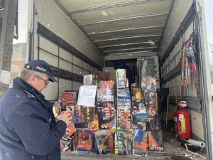 Umundurowany policjant kontroluje stoisko z fajerwerkami.