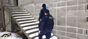 Umundurowani policjanci kontrolują pustostan.