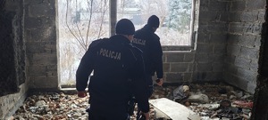 Umundurowani policjanci sprawdzają budynek niemieszkalny.