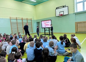 Umundurowany policjant prowadzi profilaktykę z dziećmi.