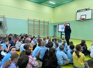 Umundurowany funkcjonariusz policji przeprowadza rozmowę w Szkole w Brzezinach.