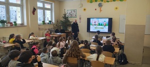 Policjant prowadzący pogadankę dotyczącą bezpiecznych Ferii.