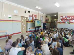 Policjant prowadzi zajęcia w szkole z dziećmi.