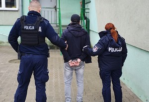 Osoba zatrzymana na podstawie listu gończego wraz z umundurowanymi funkcjonariuszami policji.