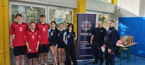 Umundurowani policjanci wraz z uczniami w strojach sportowych.
