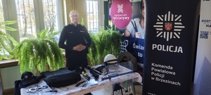 Umundurowany policjant przy stoisku Komendy Powiatowej Policji w Brzezinach.