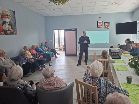 Funkcjonariusz policji przeprowadzający prelekcje o bezpieczeństwie z seniorami.