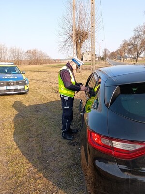 Umundurowany funkcjonariusz ruchu drogowego przeprowadza kontrolę.