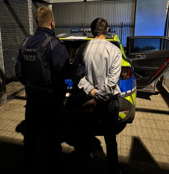 Umundurowany policjant wraz z zatrzymanym mężczyzną.