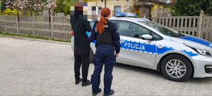 Osoba zatrzymana pod nadzorem funkcjonariusza policji.