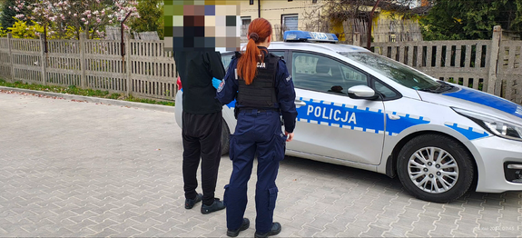 Osoba zatrzymana pod nadzorem funkcjonariusza policji.