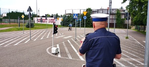 Umundurowany policjant przeprowadza egzamin na kartę rowerową.
