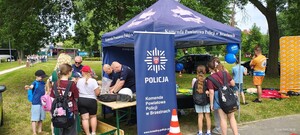 Umundurowani policjanci pracujący przy stoisku profilaktycznym.