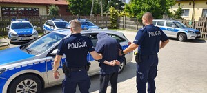 Umundurowani policjanci wraz z osobą zatrzymaną.