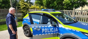 Dzieci oglądają radiowóz policyjny.