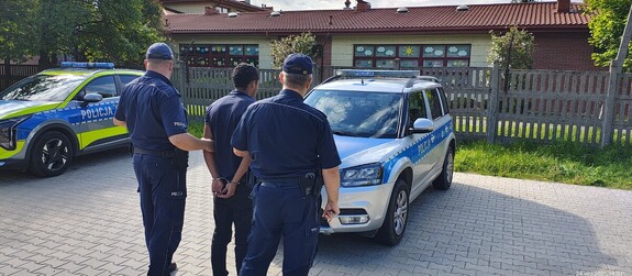 Umundurowani policjanci z osobą zatrzymaną.
