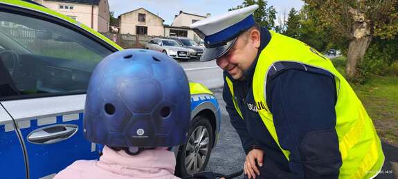 Policjant Komendy Powiatowej Policji w Brzezinach w Brzezinach wręcza kask.