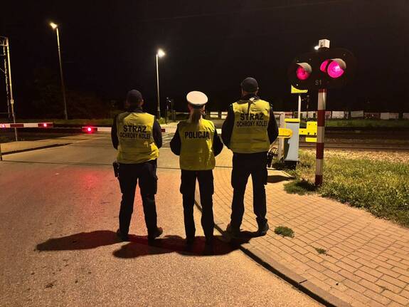 Zamknięte rogatki przejazdu kolejowego kontrolowanego przez Policję i Straż Ochrony Kolei.