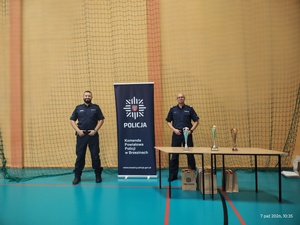 Umundurowani funkcjonariusze policji wraz z pucharami dla zwycięzców.