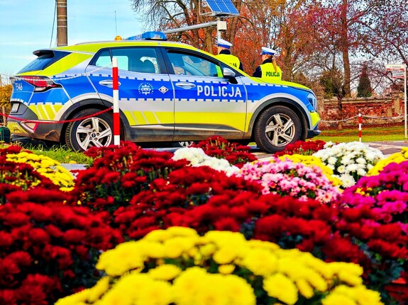 Oznakowany radiowóz policyjny wraz z dwoma policjantami.